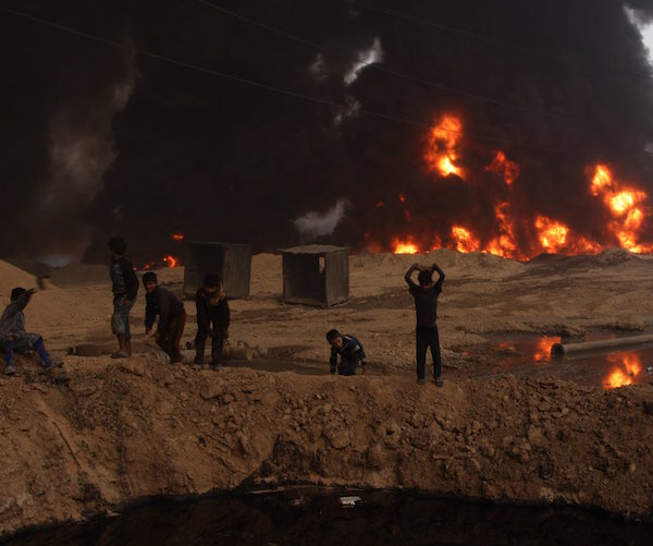 Children throwing rocks into a pool of crude oil